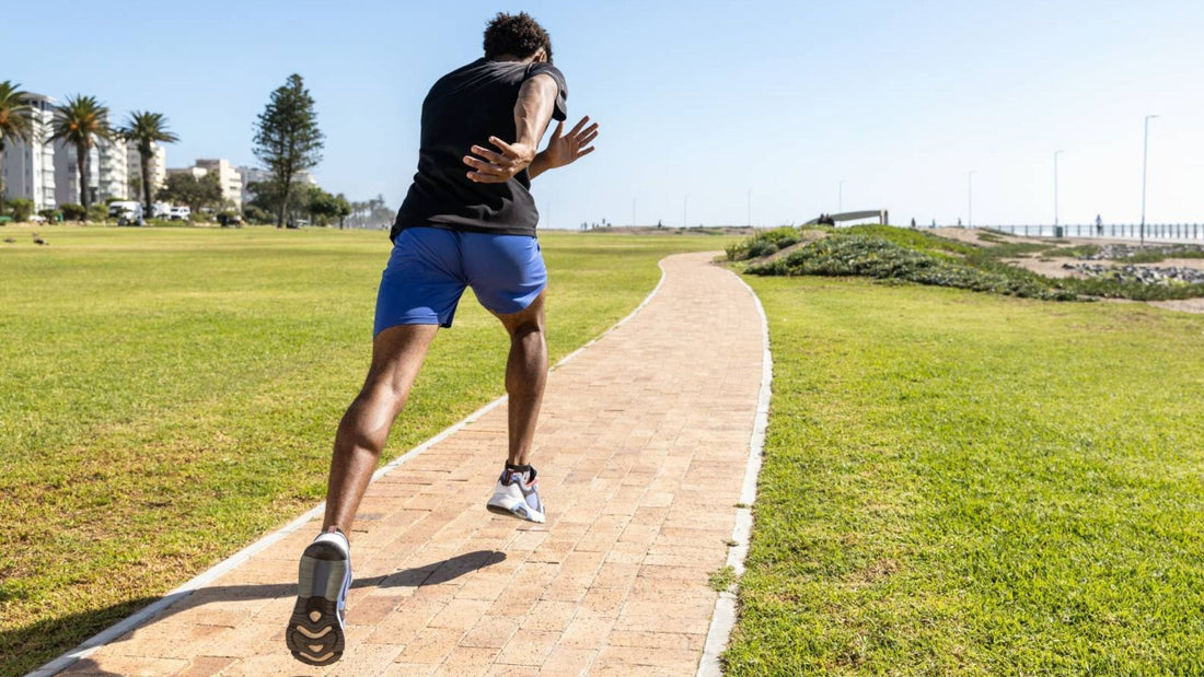 man running through the park. He is wearing sports shoes and insoles to help reduce the risk of stress fractures.